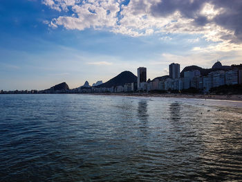 Scenic view of sea by buildings against sky during sunset