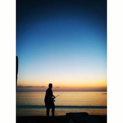 Silhouette man standing on beach against clear sky