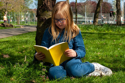 Young woman using laptop while sitting on field