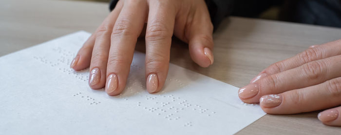 Midsection of woman holding paper with text on table