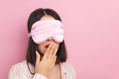 Young woman standing against pink background