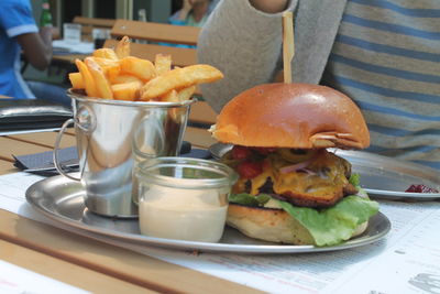 Midsection of man sitting by burger and french fries on restaurant table