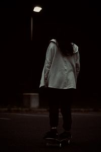 Rear view of woman standing on street at night