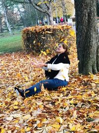 Woman sitting on tree trunk during autumn