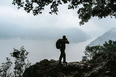 Full length of man standing by lake against mountains