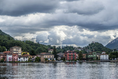 Houses by lake against sky in city