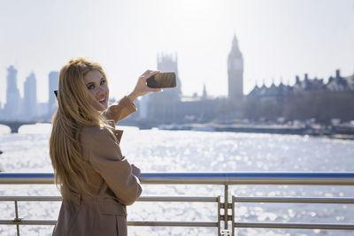 Portrait of young woman taking picture through mobile phone