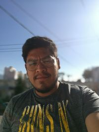 Portrait of young man wearing sunglasses standing against sky