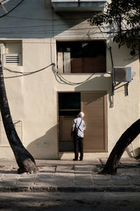 Rear view of man walking on street against building