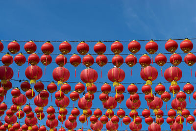 Low angle view of lanterns hanging against clear blue sky