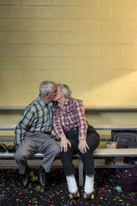 Romantic senior couple kissing on bench at skating rink