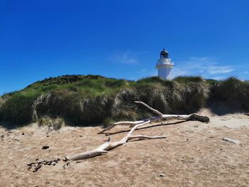 View of lighthouse on beach against blue sky