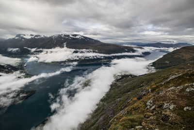 Scenic view of mountains and river against cloudy sky