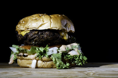 Close-up of burger on table against black background