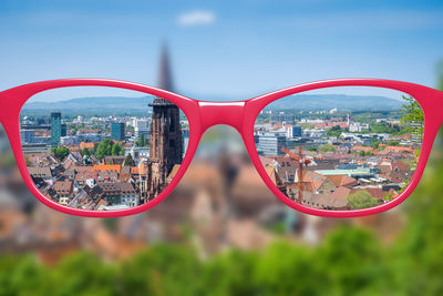 Close-up of sunglasses against cityscape seen through glass
