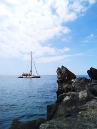 Sailboat on rock by sea against sky