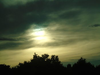 Silhouette of trees against cloudy sky