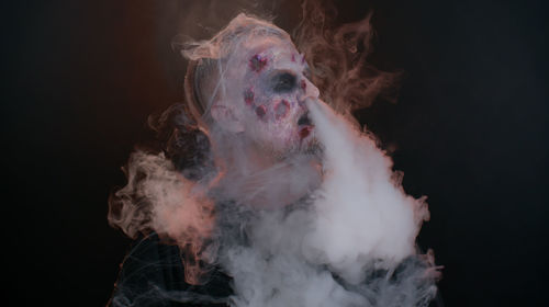 Portrait of man smoking against black background