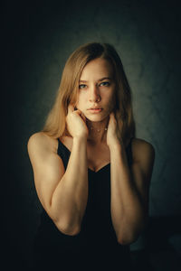 Portrait of young woman against black background