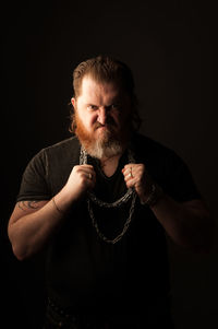 Portrait of man standing against black background