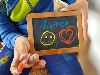 Midsection of boy holding text