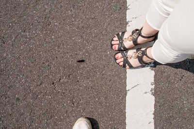 Low section of woman standing on road