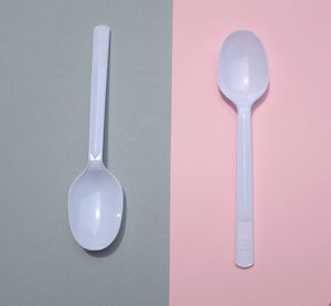 Flat lay a white plastic spoon on pink and gray paper background. minimal concept