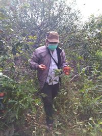 Full length of man holding fruits while walking by plants