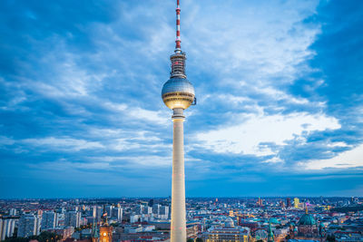 Communications tower in city against sky