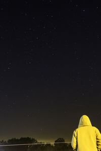 Rear view of woman standing against star field at night