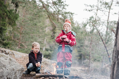 Brother and sister cooking marshmallows on a campfire in sweden