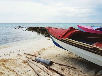 Boat moored on beach against sky