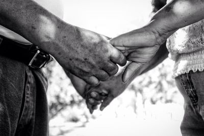 Midsection of couple holding hands while standing outdoors