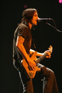 Man playing guitar against black background