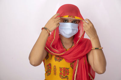 Portrait of woman wearing flu mask standing against white background
