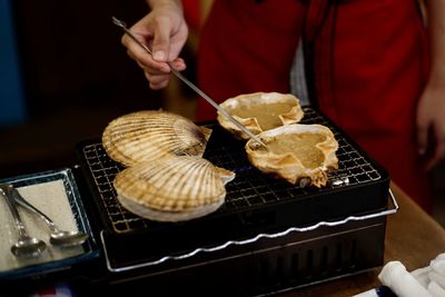 Midsection of person preparing seafood on barbecue grill