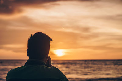 Rear view of man at beach during sunset