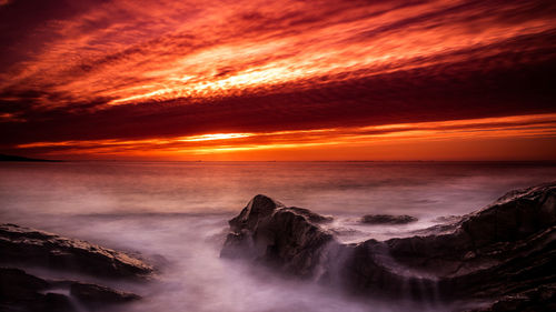 Scenic view of sea against dramatic sky during sunset