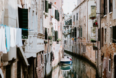 Boats moored in canal amidst buildings in city