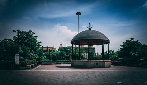Gazebo in park by building against sky