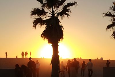 Silhouette people at beach against clear sky during sunset