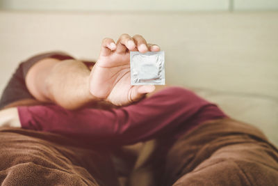 Boyfriend holding condom packet while sleeping with girlfriend