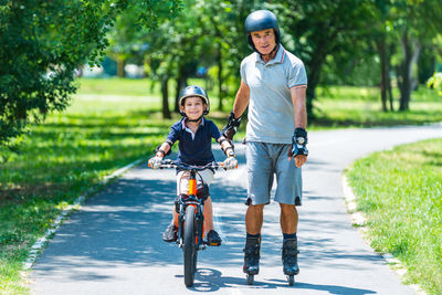 Portrait of grandfather teaching grandson to ride bicycle on road