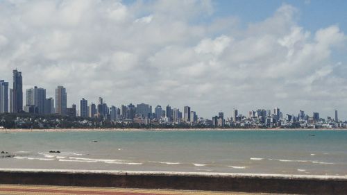 Sea by cityscape against sky