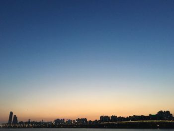 Silhouette city against clear sky during sunset