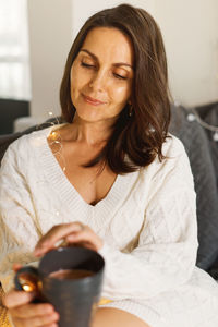 Portrait of young woman using mobile phone at home