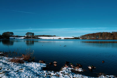 Scenic view of lake against clear blue sky