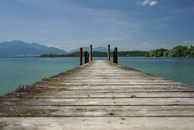 Wooden jetty on pier over lake against sky