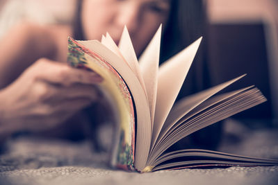 Woman turning pages of book on bed