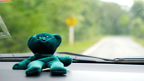 Blue toy car on road seen through window